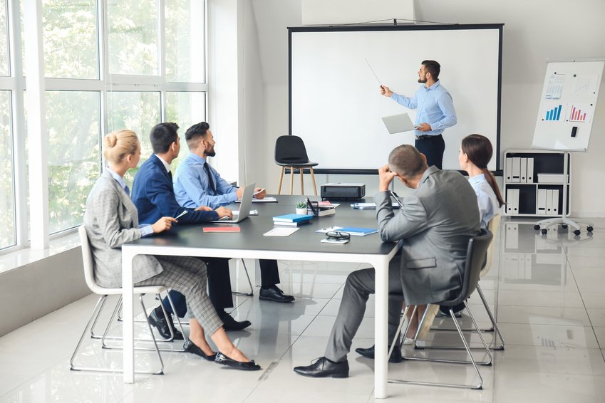 A presenter discussing work with colleagues at a meeting