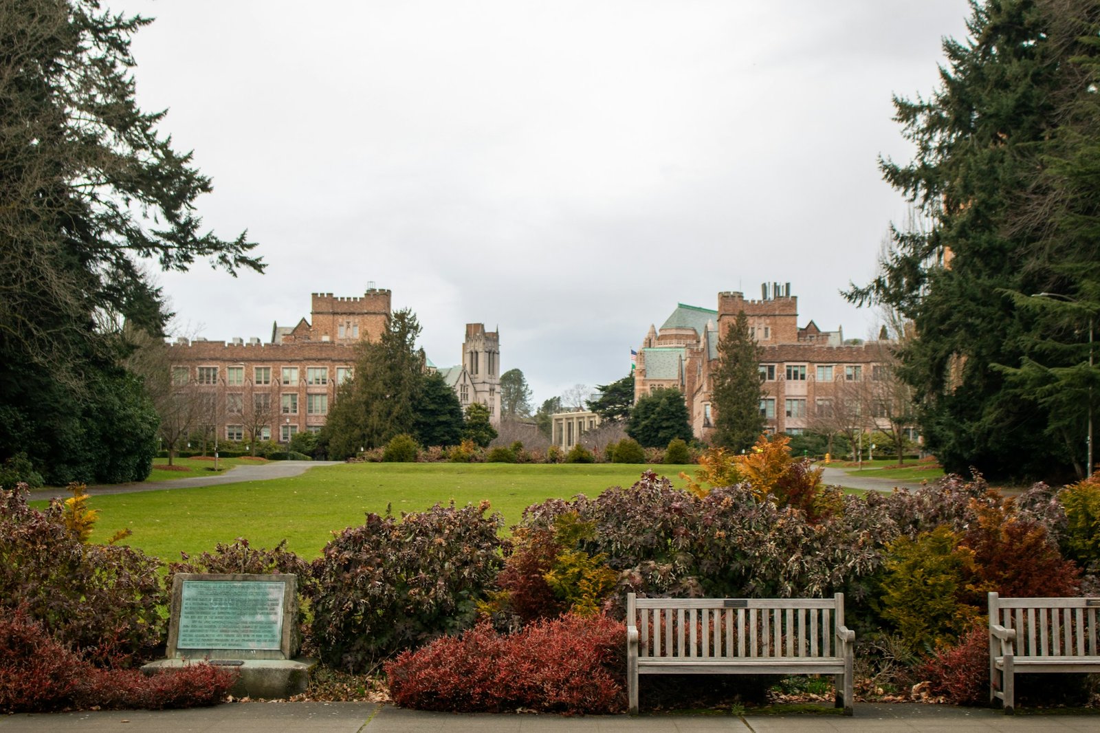 Historic university buildings and a green campus lawn beneath mature trees
