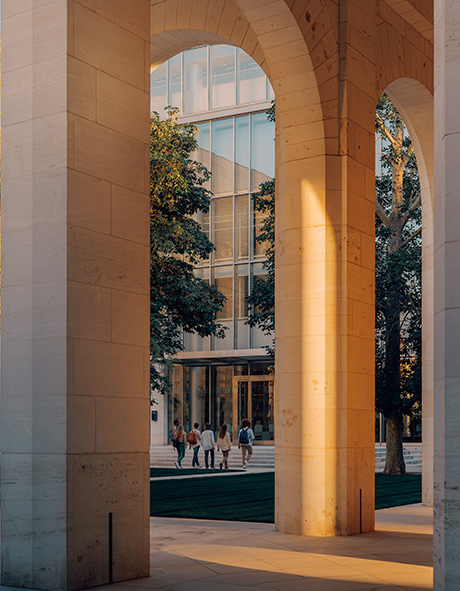 Illustrative university courtyard with students walking toward a library in warm evening light