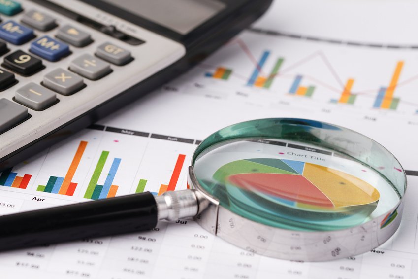A magnifying glass resting on printed charts