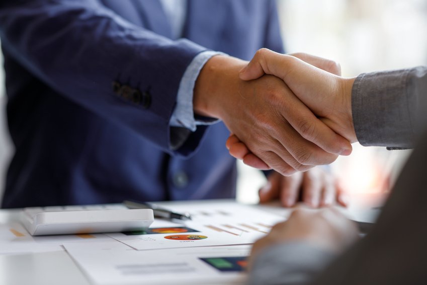 Business partners shaking hands over a meeting table