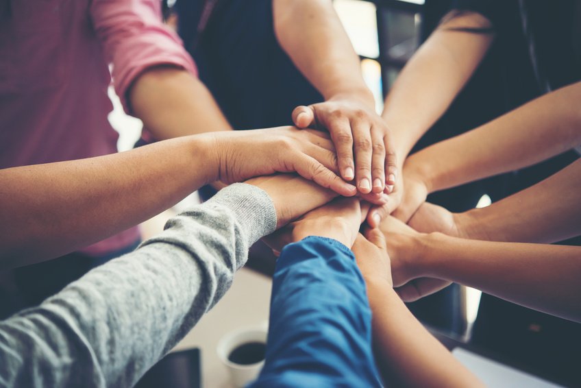A group joining their hands in a shared gesture of collaboration